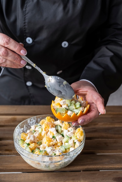 Free photo chef filling orange peel with salad