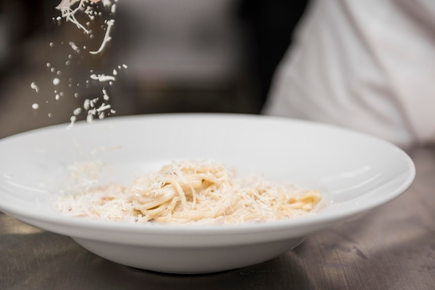 Foto gratuita cuoco unico che gratta formaggio sugli spaghetti