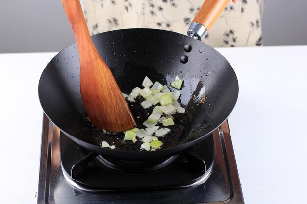 木製​キッチン​へ​ら​を​使った​シェフ​の​手​で​、​中華​鍋​を​使った​焼きそば​の​炒め​玉ねぎ​を​炒めます​。​調理​プロセス​の​コンセプト​です​。​おいしい​中華​料理​の​準備​の​舞台裏​。