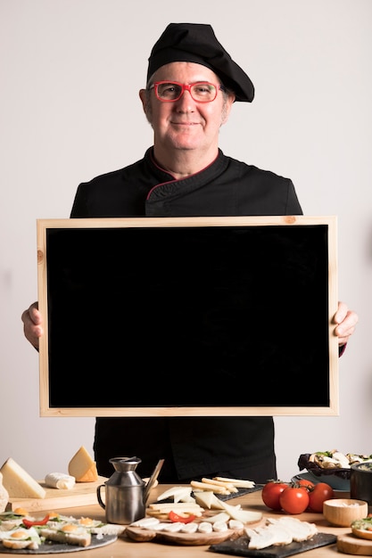 Бесплатное фото Шеф-повар держит пустую рамку
