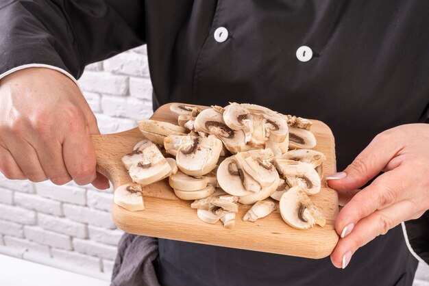 Шеф-повар держит разделочную доску с грибами