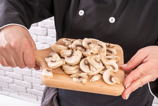 Chef holding chopping board with mushrooms