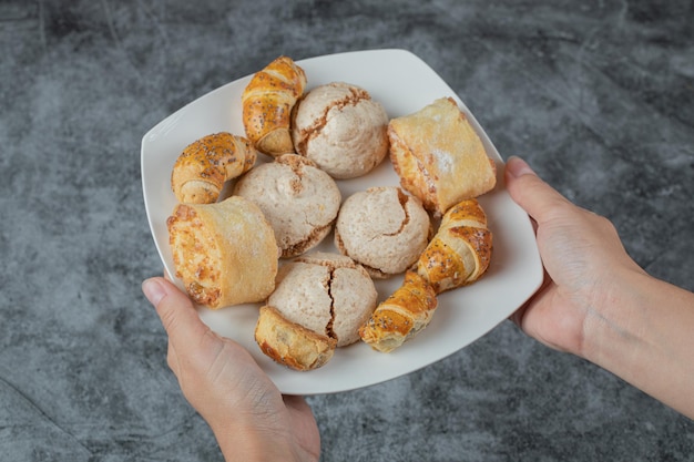 Chef holding crispy cookies with sugar powder in the hand.