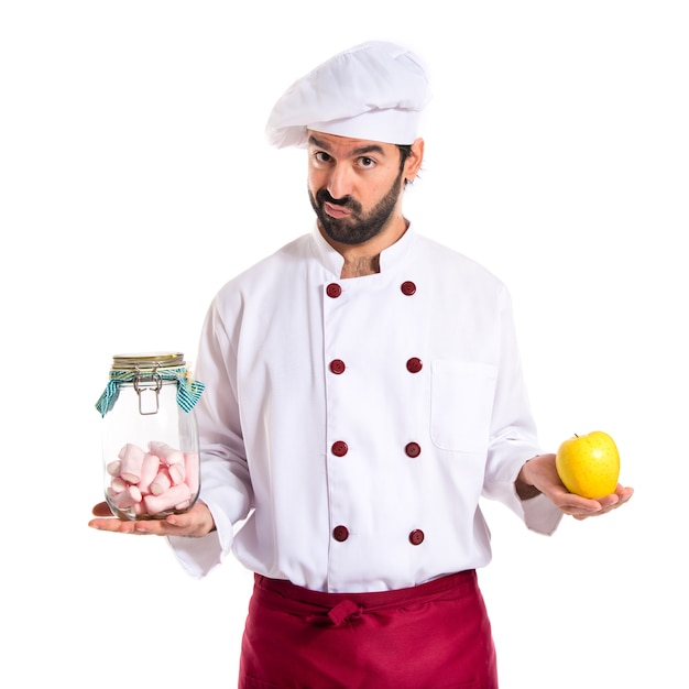 Chef holding jar glass with sweetmeats in one hand and apple in another hand