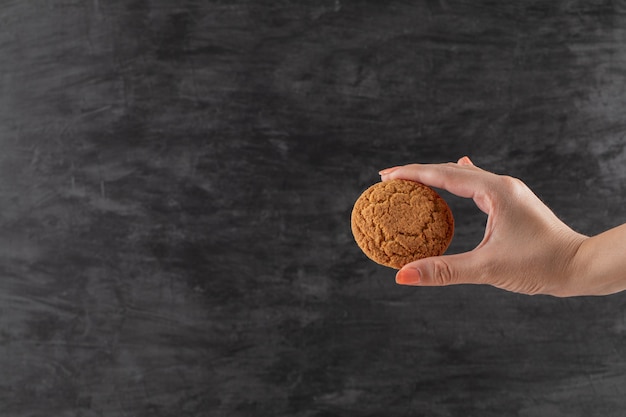 A chef holding oatmeal cookies in the hand.