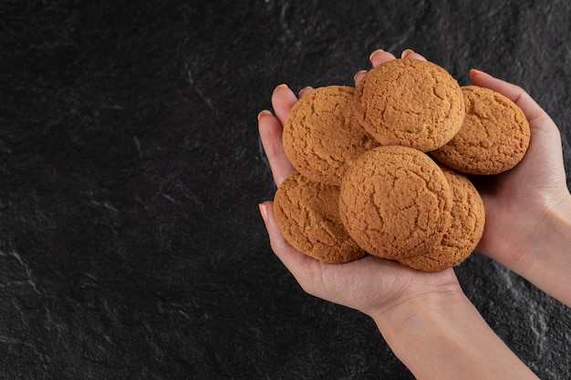 Un cuoco unico che tiene i biscotti della farina d'avena nella mano.