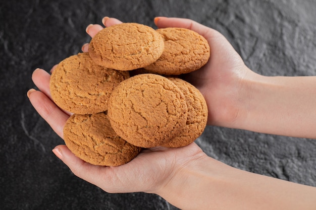 Foto gratuita un cuoco unico che tiene i biscotti della farina d'avena nella mano.