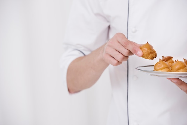 Бесплатное фото Шеф-повар держит тарелку с безе