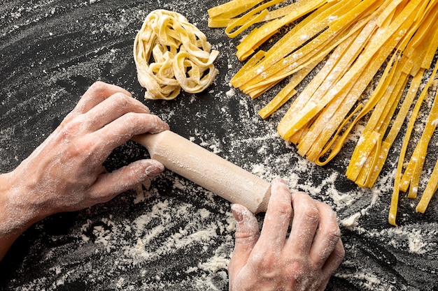 Chef holding rolling pin near pasta