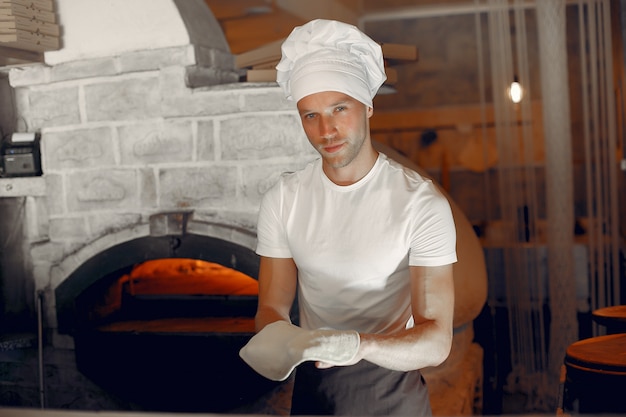Бесплатное фото Шеф-повар в белой форме готовит пиццу