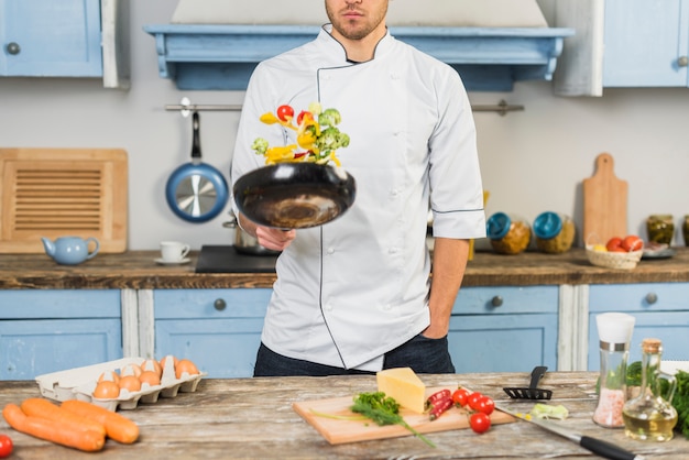 Chef in kitchen cooking with vegetables