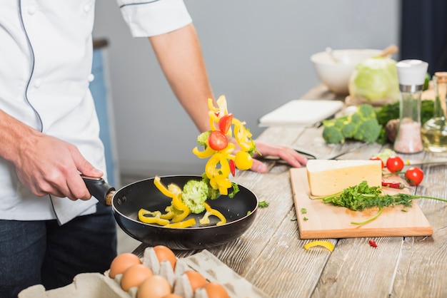 Chef in kitchen cooking with vegetables