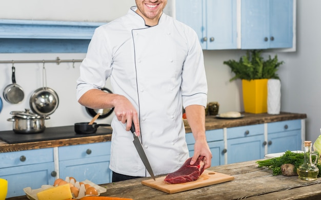 Chef in kitchen cutting meat