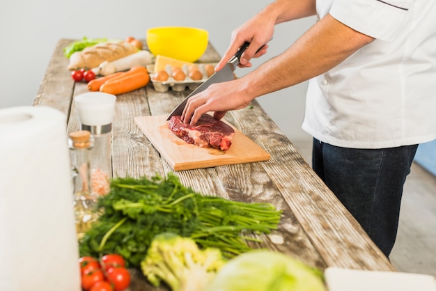 Chef in kitchen cutting meat