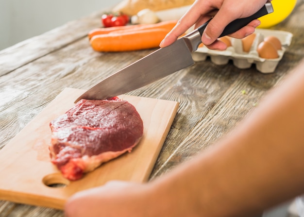 Chef in kitchen cutting meat