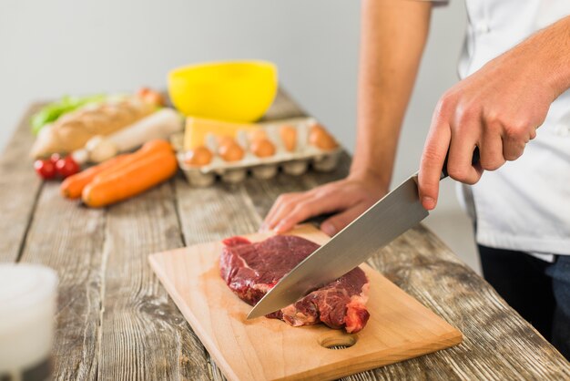 Chef in kitchen cutting meat