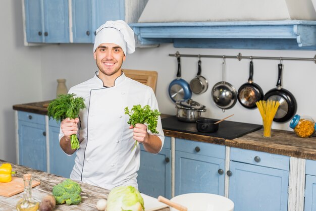 Chef in kitchen in front of vegetables