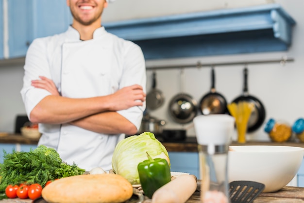 Chef in kitchen in front of vegetables