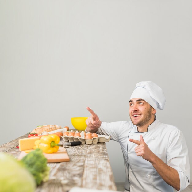 Chef in kitchen pointing towards copyspace