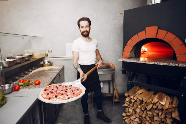 Шеф-повар на кухне готовит пиццу