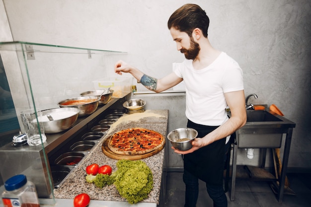 Foto gratuita lo chef in cucina prepara la pizza