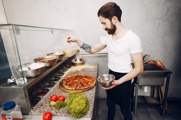 Chef in the kitchen prepares pizza