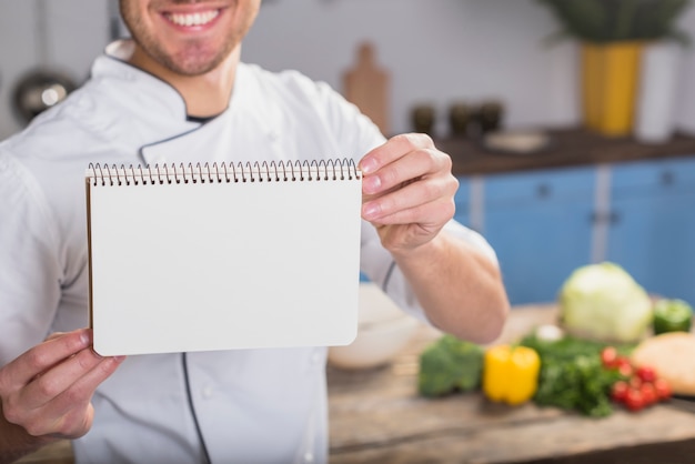 Chef in kitchen showing notepad