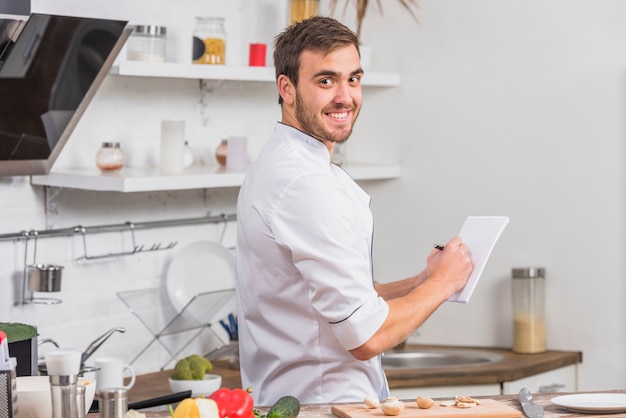 Chef in kitchen writing notes