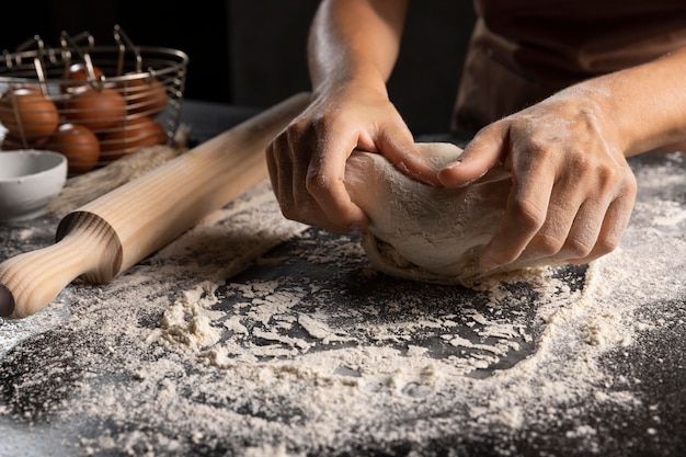 Chef kneading the dough in flour on the table