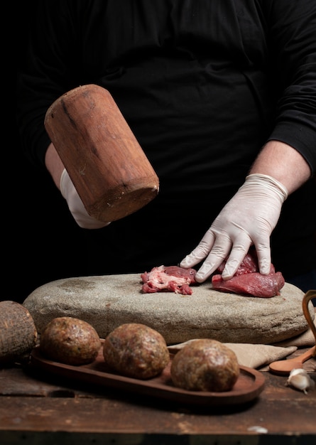 Cuoco unico che macina carne cruda con il martello di legno