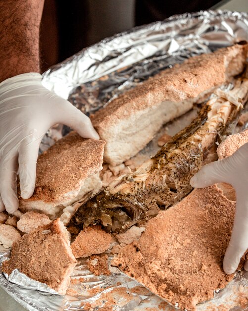 Chef opens salt from salt crusted fish revealing tender cooked fish