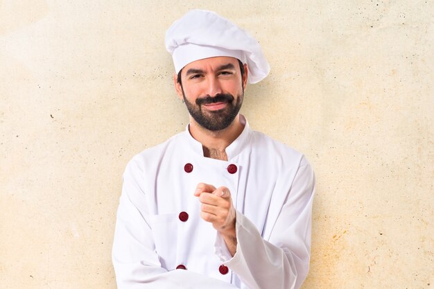 Шеф-повар, указывающий на передний план на белом фоне