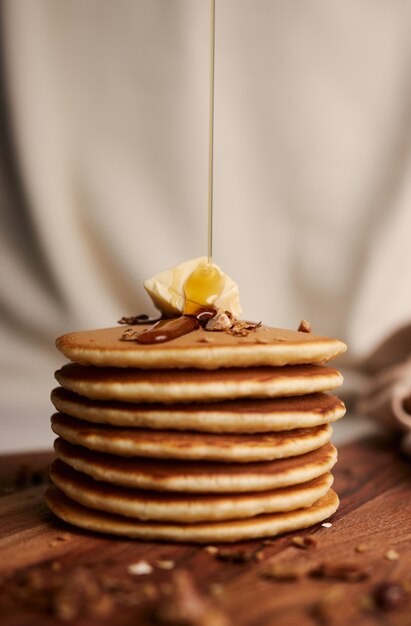 Chef pouring maple syrup on a pile of delicious pancakes