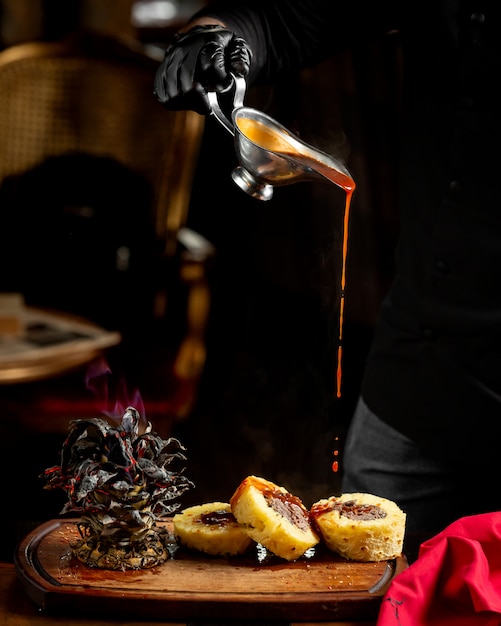 Chef pouring tomato sauce on stuffed pineapple steak slices