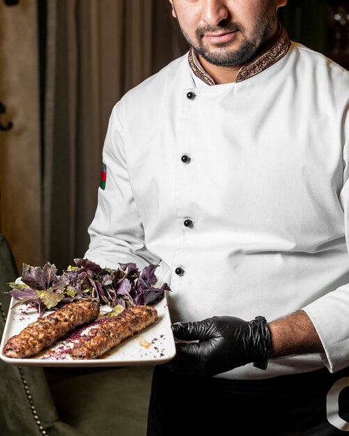 Chef presents a lula kebab served with basil