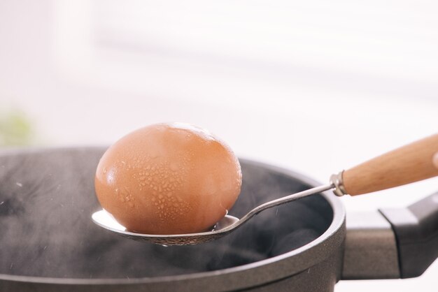 Шеф-повар кладет вареные яйца в чашку / приготовление сладкого коричневого тушеного свиного соуса (му па-ло).