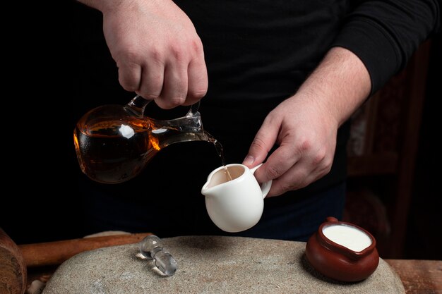 A chef putting oil from glass bottle into the ceramic jar