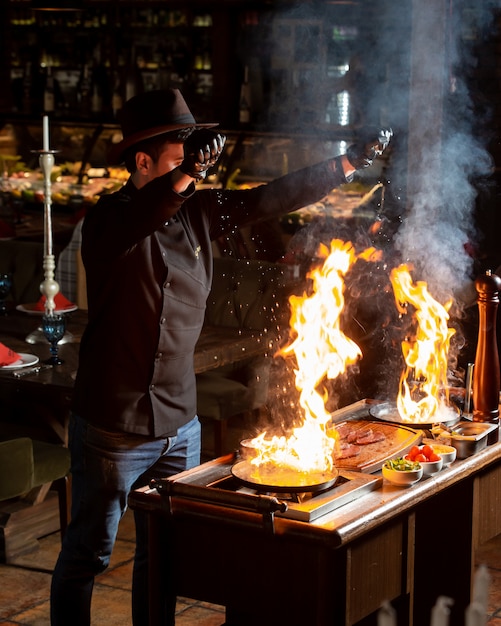 Chef putting salt into two burning pans with oil