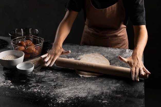 Free photo chef rolling dough in the table