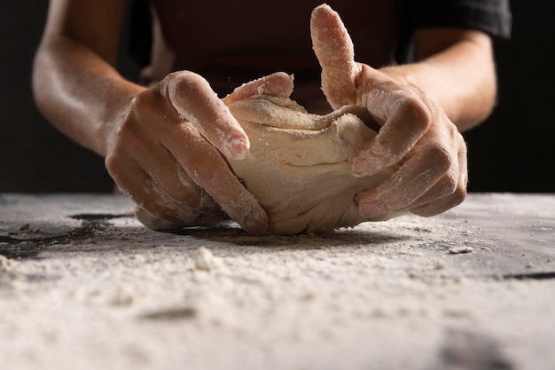 Chef's hands kneading dough with flour on the table