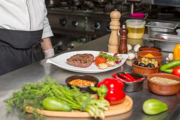 Chef served beef steak mushroom, arugula salad and tomatoes