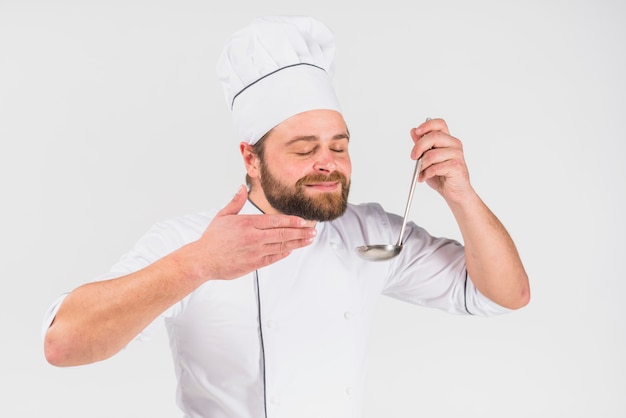 Chef smelling dish in ladle 