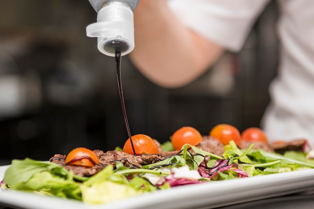 Chef squeezing sauce on salad