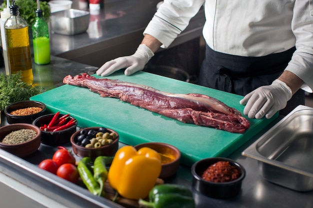 Chef in piedi in cucina pronto a preparare la bistecca di manzo