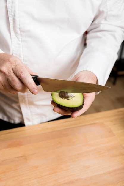 Бесплатное фото Шеф-повар вынимает семена авокадо