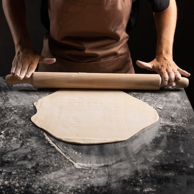 Chef using rolling pin on dough