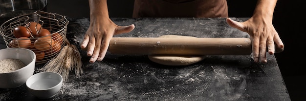 Chef using rolling pin on dough