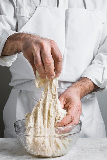 Chef in white clothes making dough