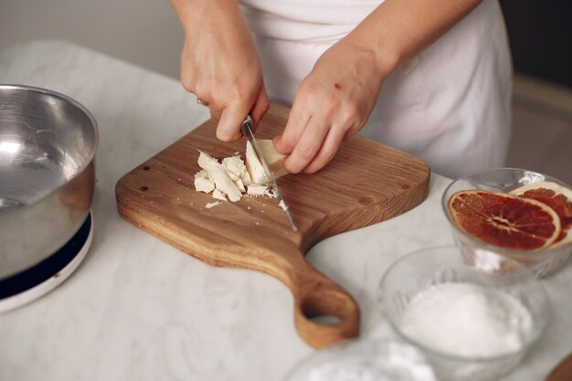 Chef in white clothes prepares a chocolate cake. Lady is preparing dessert. Woman bakes a cake.