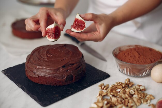 Chef in white clothes prepares a chocolate cake. Lady is preparing dessert. Woman bakes a cake.